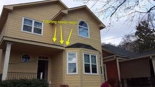Two-story yellow house with white trim. Arrows point to roof flashing needing repair, above bay window. Overcast sky, bare branches visible.